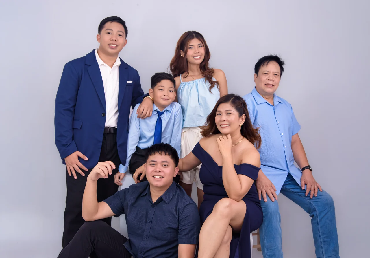 Six family members smiling together in coordinated blue outfits.